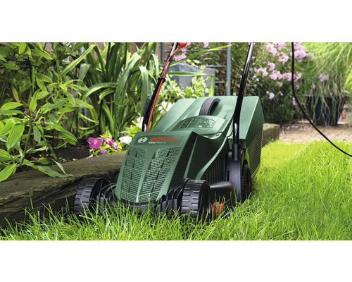 Tondeuse à gazon en cours d''utilisation dans le jardin entre les plantes