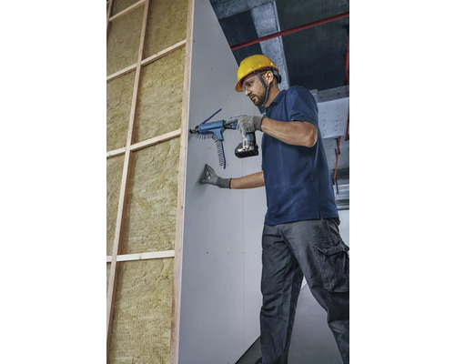 Artisan fixant une plaque de plâtre avec un tournevis à magasin sur un mur