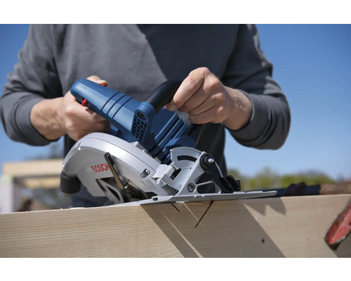 Eine Person schneidet ein Holzbrett mit einer Bosch-Handkreissäge.