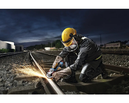 Un ouvrier meule un rail de chemin de fer avec une meuleuse d'angle, créant ainsi des étincelles.