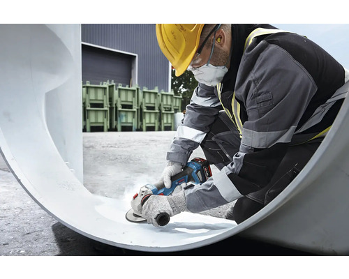 Un ouvrier du bâtiment travaille un tube avec une meuleuse d'angle