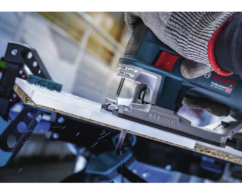 Gros plan d''une scie sauteuse coupant une pièce, actionnée par une personne portant des gants.