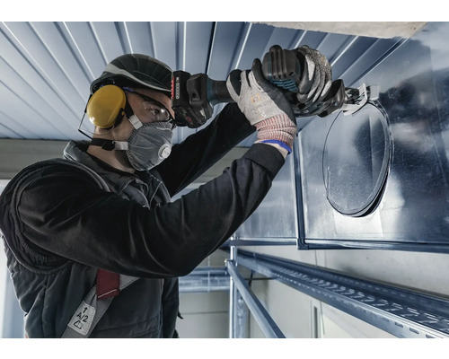 Une personne découpe un trou dans un conduit de ventilation à l''aide d''une grignoteuse.