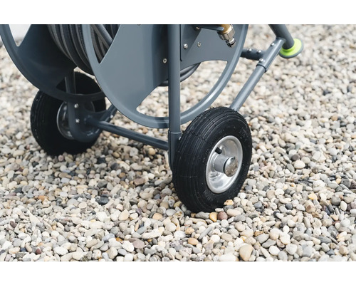 Detailaufnahme eines Gartenschlauchwagens mit Reifen auf Kies