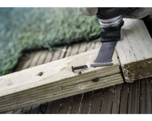 Outil électrique oscillant coupant un clou dans une planche de bois.