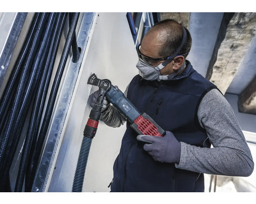 Un artisan utilise un outil multifonction pour couper dans un mur