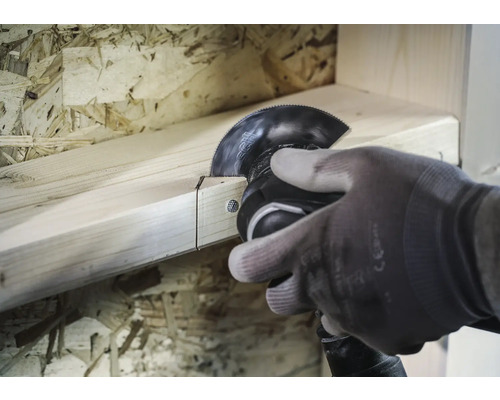 Eine Person sägt mit einem Multifunktionswerkzeug ein Holzbrett.