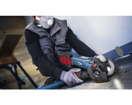 Artisan utilisant une meuleuse d''angle avec aspiration de poussière sur un plancher en bois