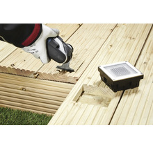 Installation d''un éclairage de terrasse dans des planches de bois avec une scie