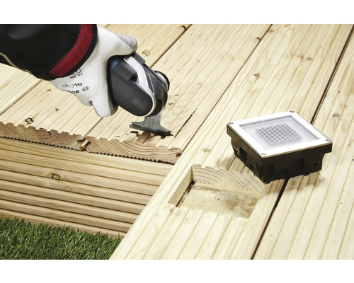 Installation d''un éclairage de terrasse dans des planches de bois avec une scie