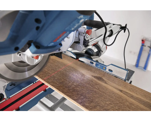 Scie à onglet coupant une planche de bois avec guidage laser.