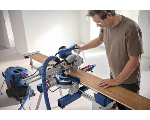Homme utilisant une scie à onglet radiale Bosch avec pièce et aspirateur
