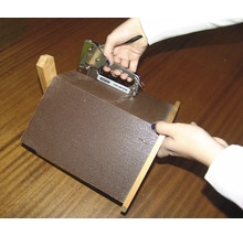 Une personne fixe un morceau de tissu sur une construction en bois avec une agrafeuse.