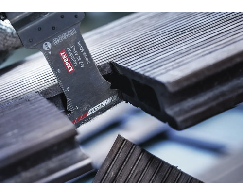 Logo Bosch. Gros plan d''une scie coupant une lame de terrasse.