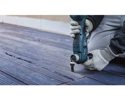 Outil électrique oscillant en cours d''utilisation sur une terrasse en bois