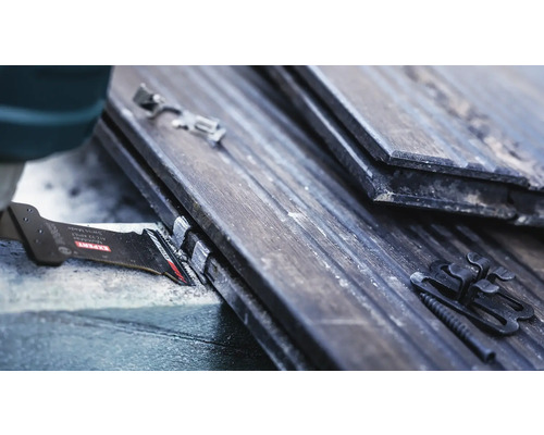 Gros plan d''une lame de scie coupant des tuiles avec des clips de fixation