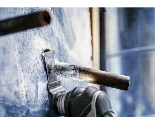 Une scie oscillante coupe un tuyau de cuivre.