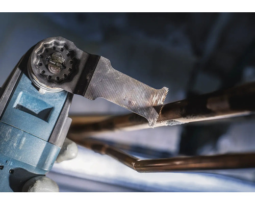 Outil électrique oscillant coupant un tuyau de cuivre.