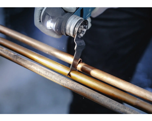 Une personne coupe un tube de cuivre avec un outil multifonction.