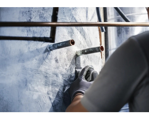 Installation de tuyaux en cuivre sur un mur par un artisan.