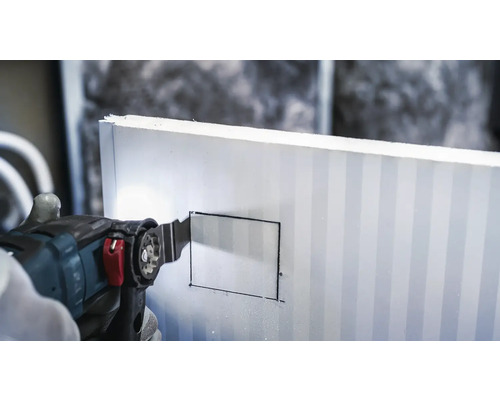 Une scie oscillante coupe une plaque isolante.