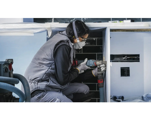 Une artisane travaille avec un outil multifonctionnel sur un lavabo dans la salle de bains.