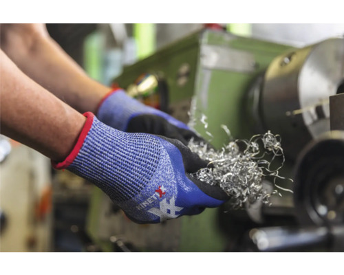 Hände mit Schutzhandschuhen halten Metallspäne vor einer Drehmaschine