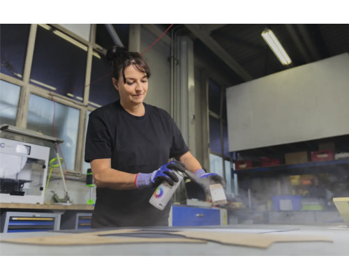 Une femme vaporise de la peinture sur une pièce à l''aide d''un aérosol.