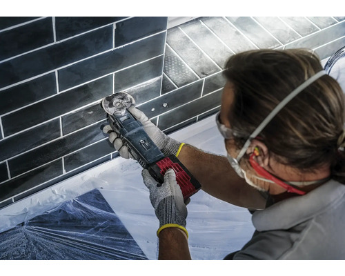 Handwerker bei der Fliesenfugenbearbeitung mit einem Multifunktionswerkzeug