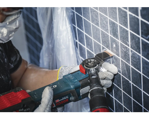 Outil multifonction oscillant en cours d''utilisation sur un mur