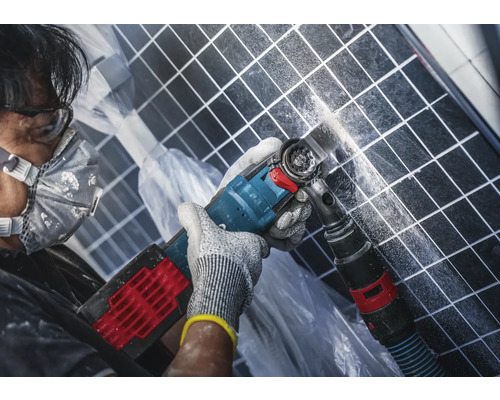 Un homme travaille sur des carreaux avec un outil multifonctionnel