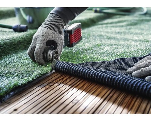 Verlegen von Kunstrasen mit Werkzeug auf einer Holzterrasse.