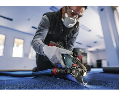 Handwerker schneidet Teppich mit einem Elektrowerkzeug