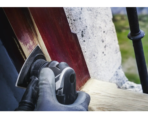 Une personne ponce du bois avec une ponceuse triangulaire.