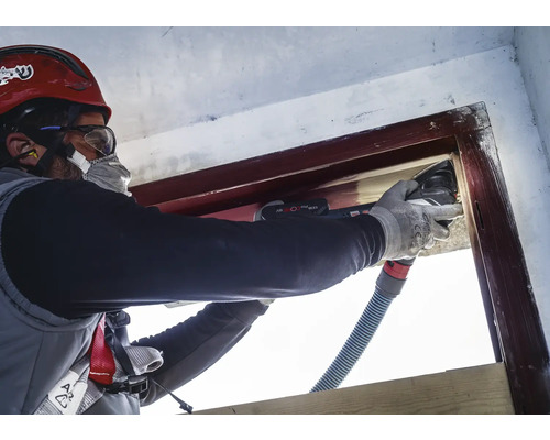 Artisan rénovant un cadre de fenêtre avec un outil multifonction