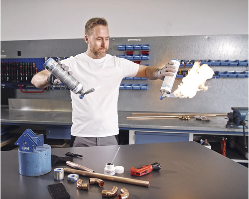 Homme soudant des tubes de cuivre avec un chalumeau à gaz