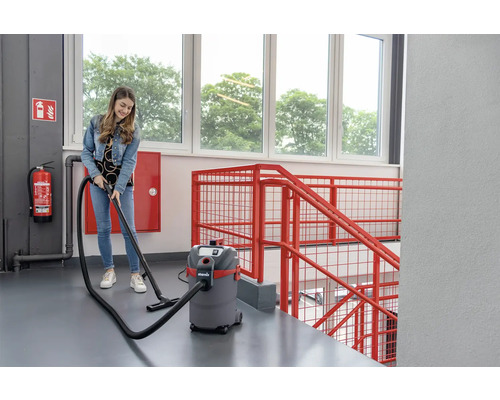 Eine Frau benutzt einen Nass Trockensauger in einem Treppenhaus.