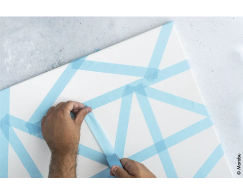 Person klebt Malerkrepp auf eine Leinwand.