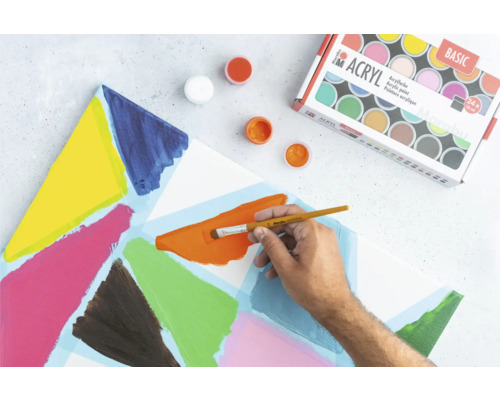 Acrylfarben, Pinsel und bemalte Leinwand auf einer Arbeitsfläche