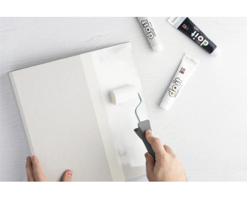 Une personne peint une plaque avec un rouleau à peinture et de la peinture Do it