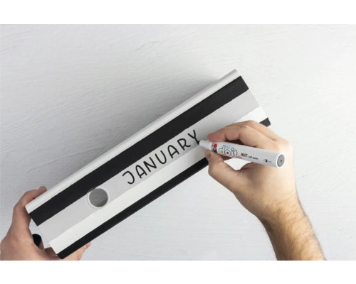 Une main écrit le mot janvier sur un classeur avec un stylo