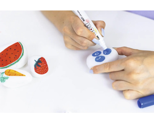 Pierres peintes avec des motifs de fruits et une personne peignant une pierre avec un stylo.