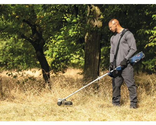 Mann bedient einen Akku-Rasentrimmer in einem Garten