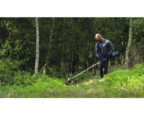Mann benutzt einen Akku-Rasentrimmer im Garten.