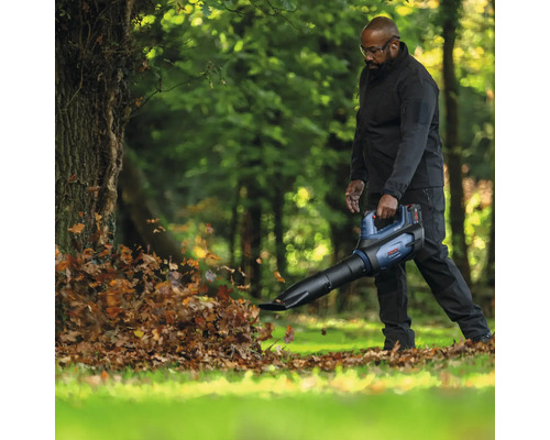 Mann benutzt Laubbläser im Garten zum Entfernen von Laub