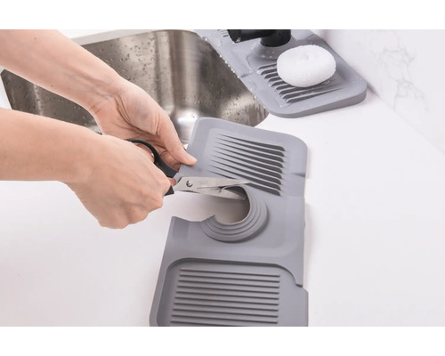 Le tapis d''évier en plastique à découper est ajusté avec des ciseaux.