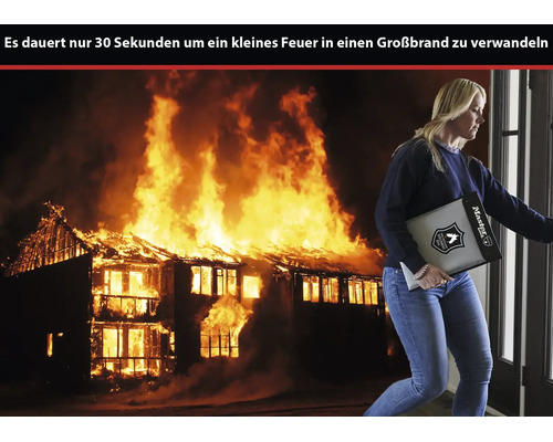 Eine Frau trägt eine feuerfeste Dokumententasche von Master Lock vor der Kulisse eines brennenden Hauses.
