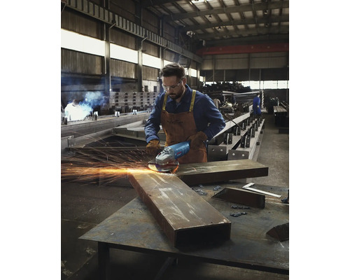 Un homme meule du métal avec une meuleuse d''angle dans un atelier.