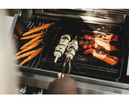 Gemüse wie Karotten, Zucchini-Spieße und Tomaten werden auf einem Grill zubereitet.
