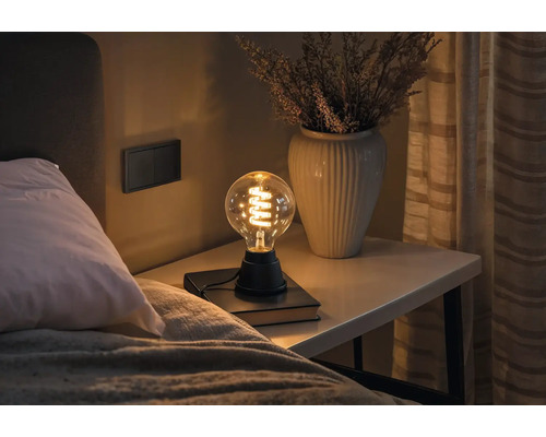 Table de chevet avec lampe et vase dans une chambre